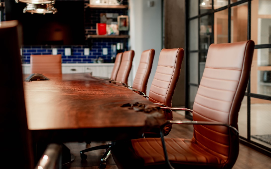 A conference room with a large wooden table and leather chairs - Photo by Bennie Bates on Unsplash