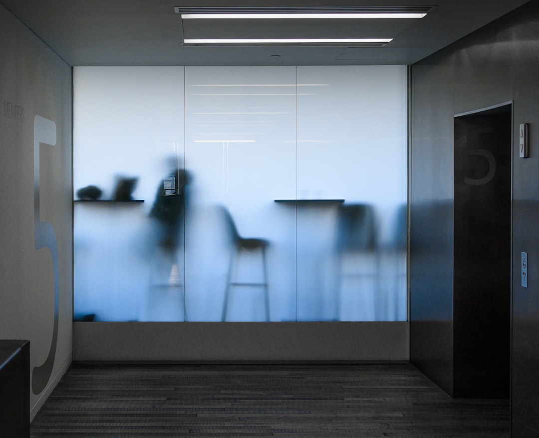 Silhouettes of people and chairs visible through frosted glass in a modern office