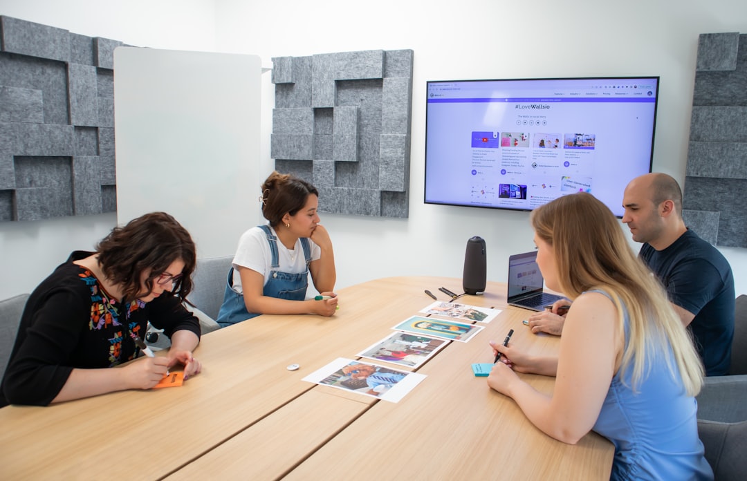 a group of people sitting around a wooden table - Photo by Walls.io on Unsplash