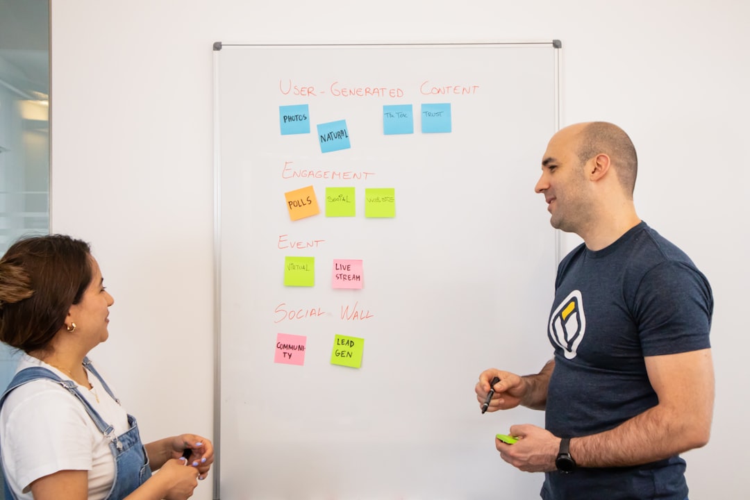 a man standing next to a woman in front of a whiteboard - Photo by Walls.io on Unsplash