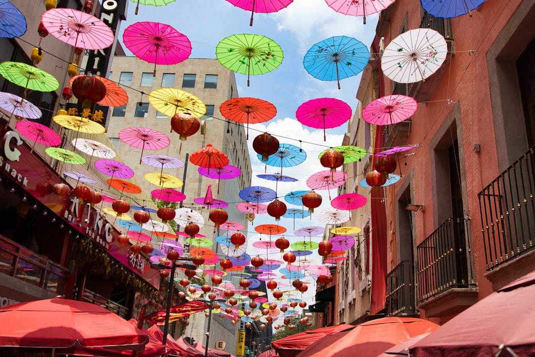 Colorful paper umbrellas and lanterns hanging over a vibrant marketplace street