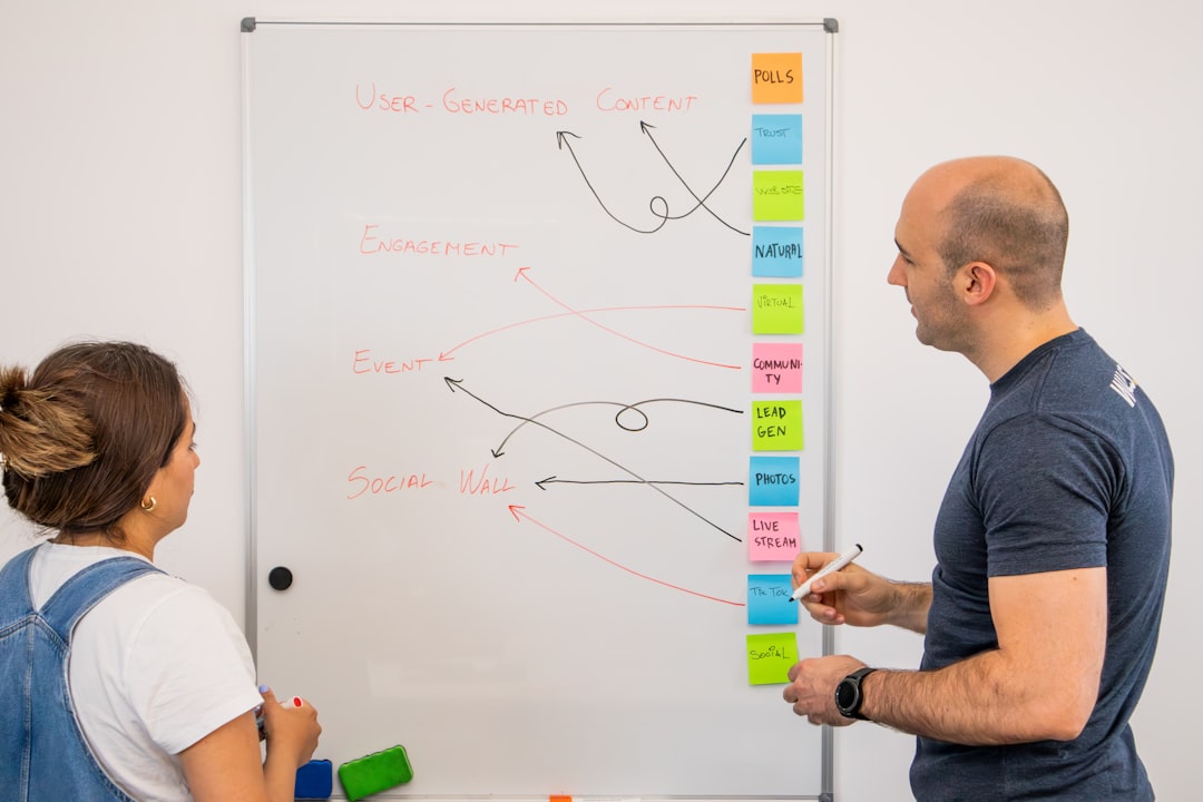 a man and a woman standing in front of a whiteboard - Photo by Walls.io on Unsplash