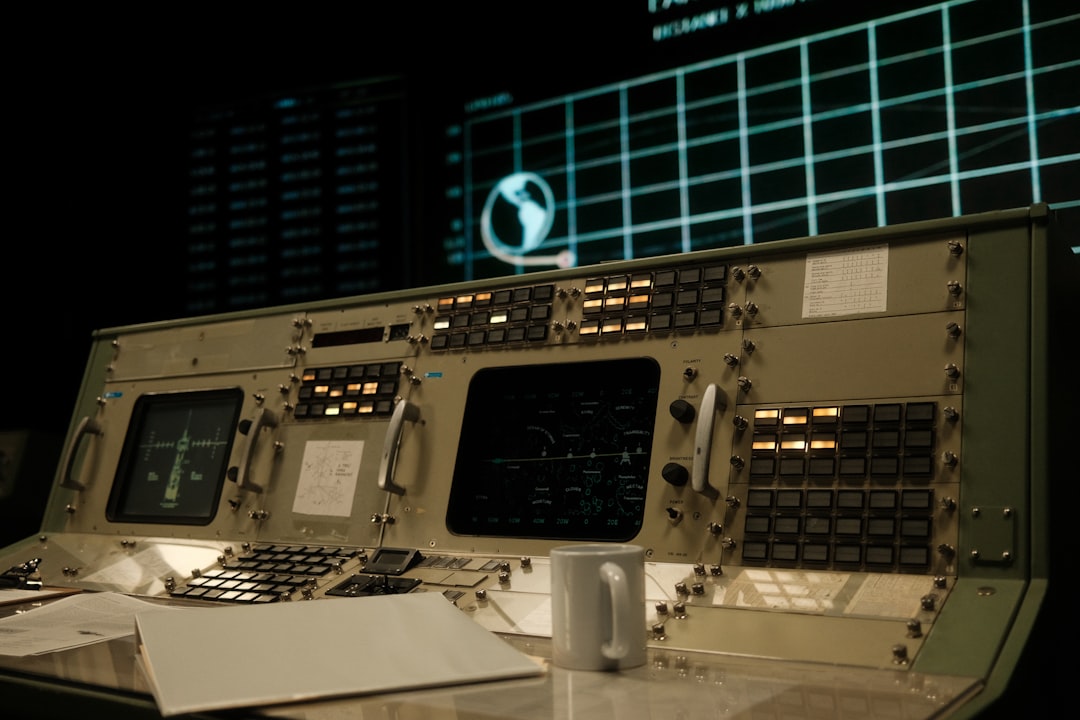 Mission control panel with illuminated buttons and screens displaying orbital data