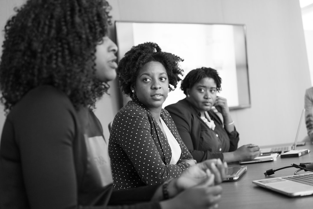 grayscale photography of two women on conference table looking at talking woman - Photo by Christina @ wocintechchat.com on Unsplash